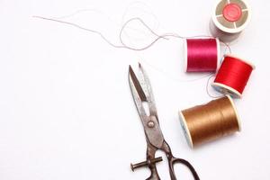 Multi-colored threads and old scissors spread out on a white floor, retro scissors, flat lay, copy space. photo