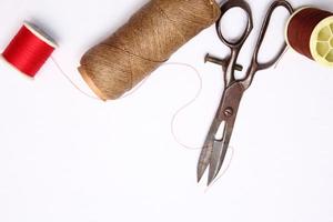 Multi-colored threads and old scissors spread out on a white floor, retro scissors, flat lay, copy space. photo