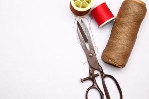 Multi-colored threads and old scissors spread out on a white floor, retro scissors, flat lay, copy space. photo