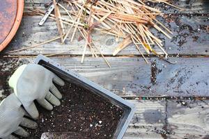 Plant pots with soil prepared for planting and gloves, pickle placed on a wooden balcony scattered with soil. photo