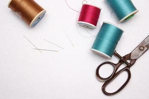 Multi-colored threads and old scissors spread out on a white floor, retro scissors, flat lay, copy space. photo