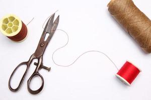 Multi-colored threads and old scissors spread out on a white floor, retro scissors, flat lay, copy space. photo
