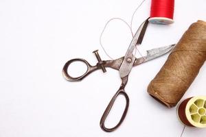 Multi-colored threads and old scissors spread out on a white floor, retro scissors, flat lay, copy space. photo