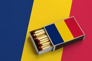 Chad flag  is shown in an open matchbox, which is filled with matches and lies on a large flag photo