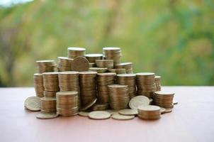 Big amount of shiny ukrainian old 1 hryvnia coin stacks close up on wooden table on green trees backdrop. The concept of business and rich life in Ukraine photo