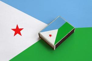 Djibouti flag  is pictured on a matchbox that lies on a large flag photo