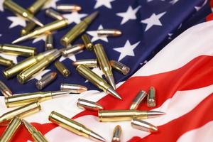 Many yellow 9mm and 5.56mm bullets and cartridges on United States flag. Concept of gun trafficking on USA territory or special ops photo