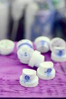 The soiled blue nozzles from the paint sprayer lies on a purple plank on a background of a many dirty spray cans photo