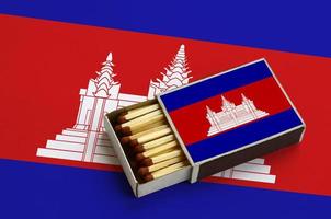 Cambodia flag  is shown in an open matchbox, which is filled with matches and lies on a large flag photo