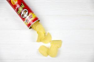 KHARKIV, UKRAINE - MAY 02, 2021 Pringles original flavour. Cardboard tube can with Pringles potato chips on white table. Pringles is a brand of potato snack chips owned by the Kellogg Company photo