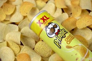 KHARKIV, UKRAINE - MAY 02, 2021 Pringles cheesy cheese flavour. Cardboard tube can on many Pringles potato chips background. Pringles is a brand of potato snack chips owned by the Kellogg Company photo