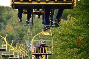 People ride on a cable car. The legs of passengers hang over the mountain forest photo