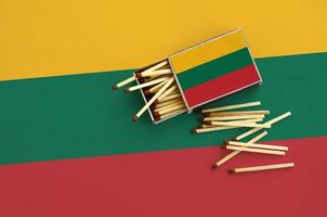 Lithuania flag  is shown on an open matchbox, from which several matches fall and lies on a large flag photo