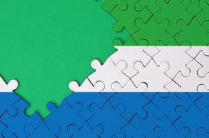 Sierra Leone flag  is depicted on a completed jigsaw puzzle with free green copy space on the left side photo
