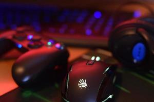 KHARKIV, UKRAINE - MAY 2, 2021 Gamesir g3s video game controller and Bloody p93 gaming mouse on office table with a4tech keyboard and headphones photo