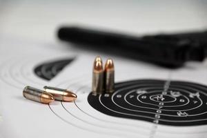 Gun and many bullets shooting targets on white table in shooting range polygon. Training for aiming and shooting photo