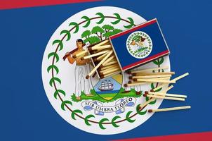 Belize flag  is shown on an open matchbox, from which several matches fall and lies on a large flag photo