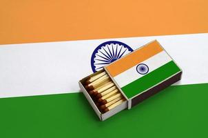 India flag  is shown in an open matchbox, which is filled with matches and lies on a large flag photo