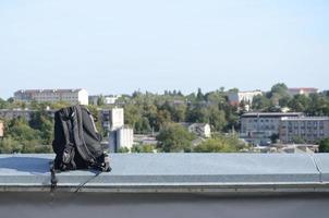 la mochila negra se encuentra en el borde metálico de la azotea de un edificio residencial de varios pisos cuando hace sol foto