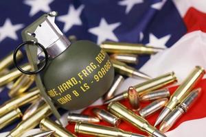 granada de fragmentación m67 y muchas balas y cartuchos amarillos en la bandera de estados unidos. concepto de tráfico de armas en territorio estadounidense o operaciones especiales foto