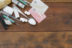 muchas pastillas y dispositivos de sustancias estupefacientes para la preparación de drogas se encuentran en una mesa de madera antigua foto