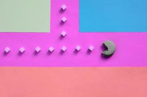 A composition of macaroon with an open mouth that is going to eat sugar cubes on a pink, lime, blue and coral background photo