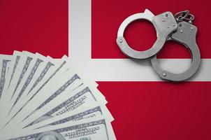 Denmark flag  with handcuffs and a bundle of dollars. The concept of illegal banking operations in US currency photo
