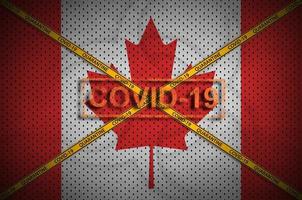 Canada flag and Covid-19 stamp with orange quarantine border tape cross. Coronavirus or 2019-nCov virus concept photo