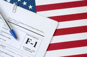I-20 Certificate of eligibility for nonimmigrant student status blank form lies on United States flag with blue pen from Department of Homeland Security photo