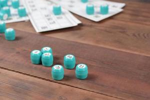 Many barrels with numbers and cards for lotto or russian bingo table game on wooden surface. Russian lotto has similar rules to classical worldwide bingo photo