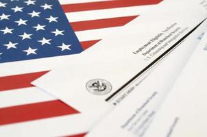 I-9 Employment Eligibility Verification blank form lies on United States flag with envelope from Department of Homeland Security photo