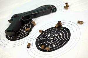 Gun and many bullets shooting targets on white table in shooting range polygon. Training for aiming and shooting photo