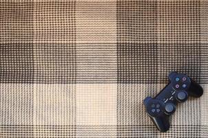 Video game controller lies on a checkered plaid photo