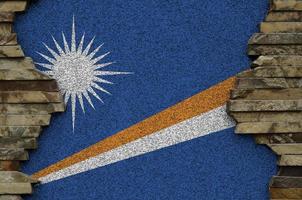 Marshall Islands flag depicted in paint colors on old stone wall closeup. Textured banner on rock wall background photo