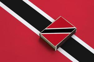 Trinidad and Tobago flag  is pictured on a matchbox that lies on a large flag photo