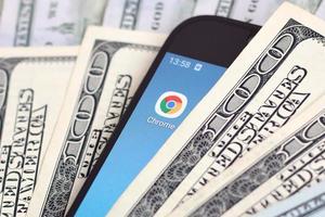 KHARKIV, UKRAINE - MAY 2, 2021 Smartphone screen with Google chrome app and lot of hundred dollar bills. Business and social networking concept photo