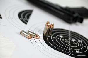 Gun and many bullets shooting targets on white table in shooting range polygon. Training for aiming and shooting photo