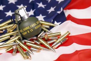 M67 frag grenade and many yellow bullets and cartridges on United States flag. Concept of gun trafficking on USA territory or spec ops photo