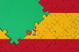 Spain flag  is depicted on a completed jigsaw puzzle with free green copy space on the left side photo