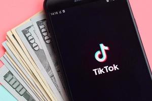 KHARKIV, UKRAINE - MAY 2, 2021 Tiktok application on samsung smartphone screen and dollar bills. TikTok is a popular video-sharing social networking service owned by ByteDance