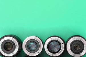 Several photographic lenses lie on a bright turquoise background. Copy space photo