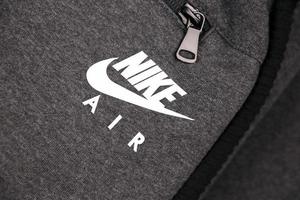 KHARKOV, UKRAINE - DECEMBER 20, 2020 Nike air logo on grey sports wear fragment. Nike is American multinational corporation engaged in manufacturing and worldwide marketing of clothes and footwear photo