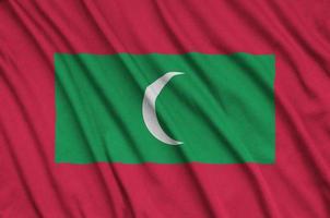 Maldives flag  is depicted on a sports cloth fabric with many folds. Sport team banner photo