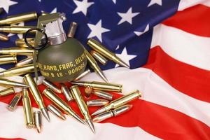 M67 frag grenade and many yellow bullets and cartridges on United States flag. Concept of gun trafficking on USA territory or spec ops photo