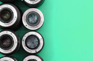 Several photographic lenses lie on a bright turquoise background. Copy space photo