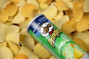 KHARKIV, UKRAINE - MAY 02, 2021 Pringles sour cream onion flavour. Cardboard tube can on many Pringles potato chips background. Pringles is a brand of potato snack chips owned by Kellogg Company photo