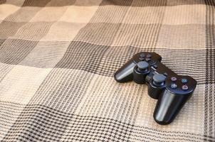 Video game controller lies on a checkered plaid photo