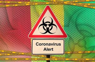 Guinea flag and Covid-19 biohazard symbol with quarantine orange tape. Coronavirus or 2019-nCov virus concept photo