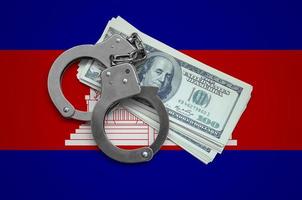 Cambodia flag  with handcuffs and a bundle of dollars. Currency corruption in the country. Financial crimes photo