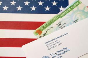 United States Permanent resident green card from dv-lottery lies on United States flag with envelope from Department of Homeland Security photo